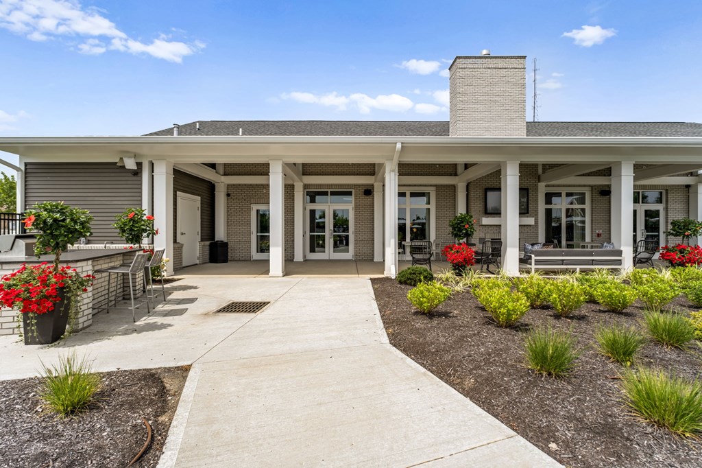 A building with a covered walkway and flower beds in front.