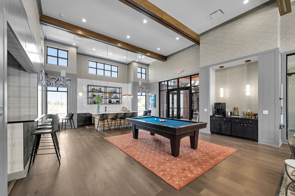 A room with a pool table and a bar area.