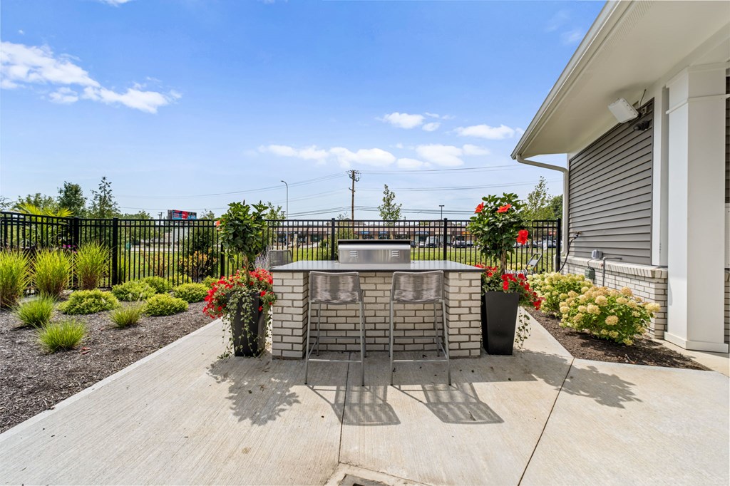 A black fence with a gate and a brick pillar with a planter on top.