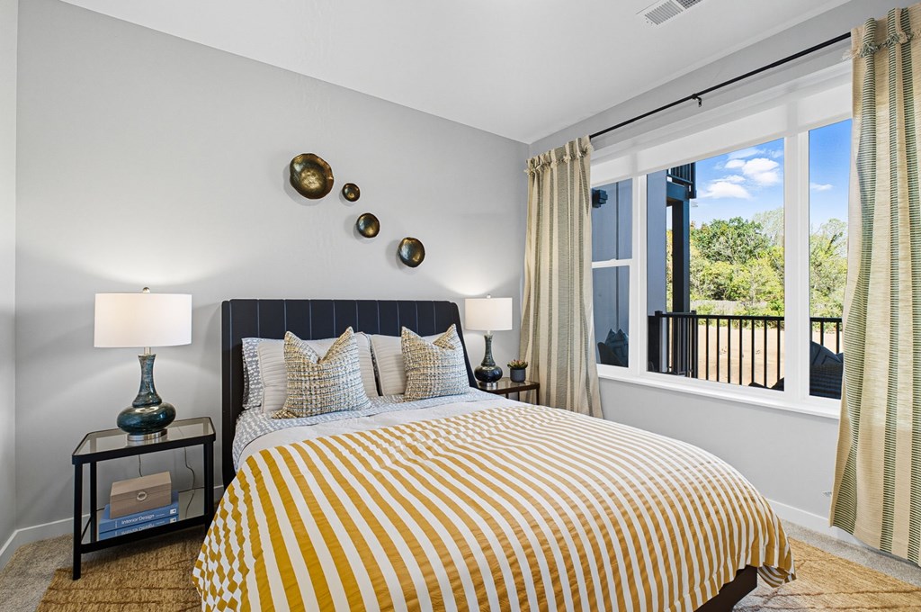 A bedroom with a bed, two lamps, and a window with curtains.