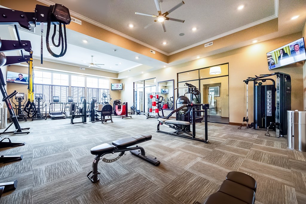 A gym with a variety of equipment including treadmills, weights, and exercise machines.