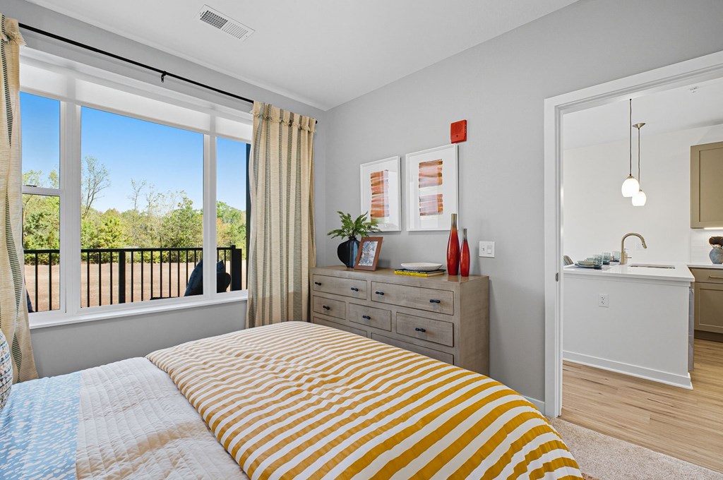 A bedroom with a bed, dresser, and window.