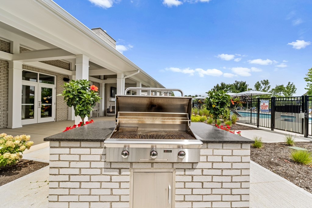 A modern outdoor kitchen with a built-in grill and a white brick exterior.