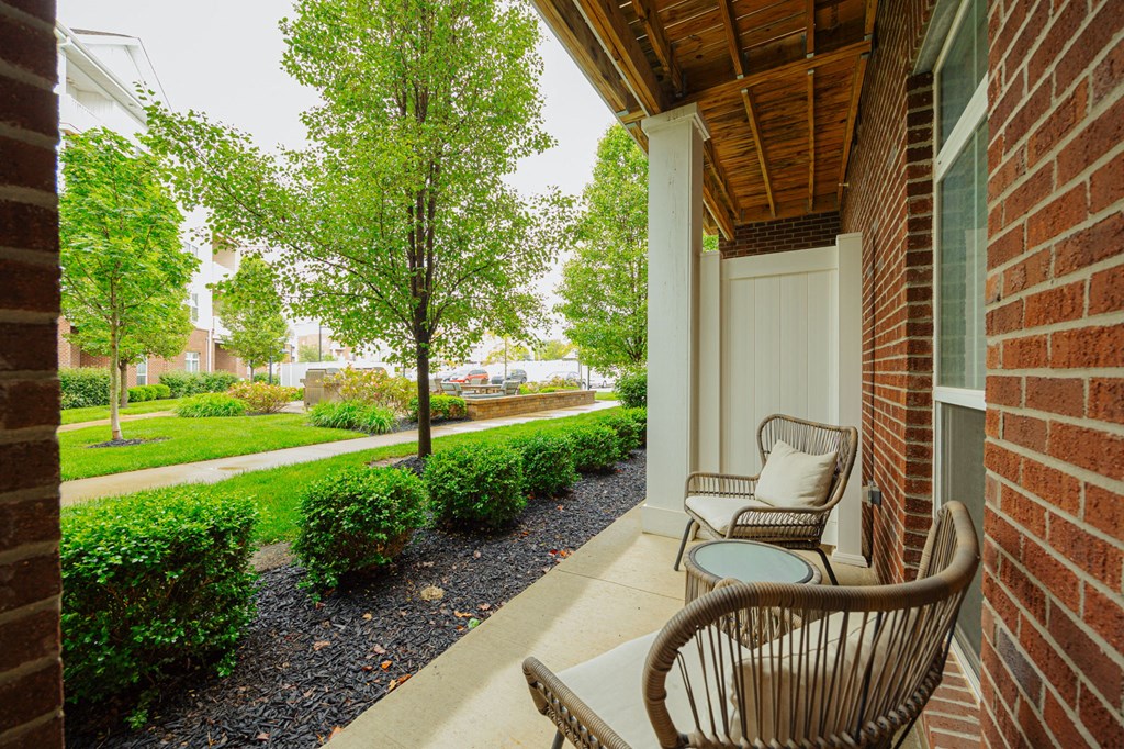 a porch with two chairs and a table on the side of a building