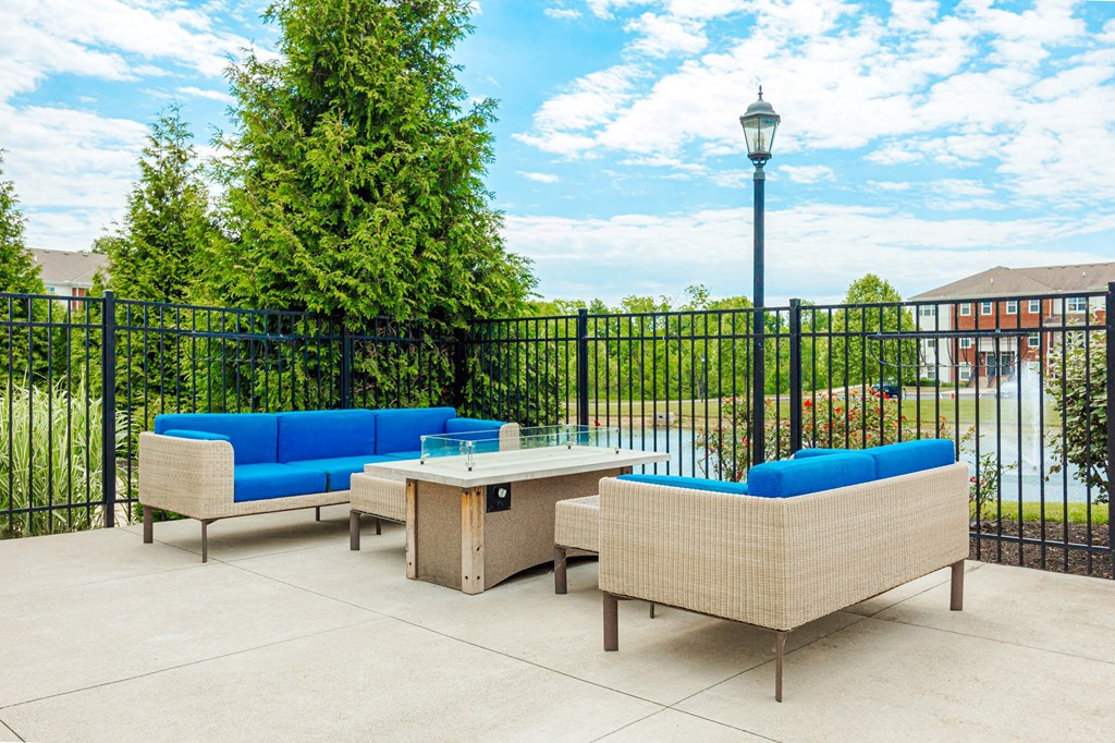 a patio with couches and a table in front of a fence