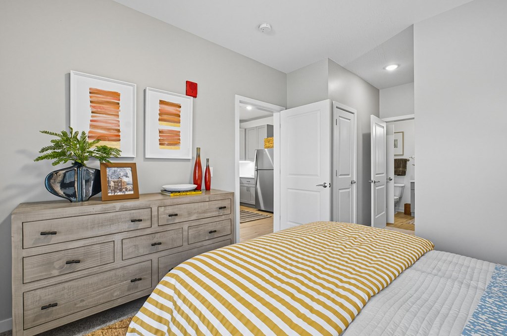 A bedroom with a bed, dresser, and two framed pictures on the wall.