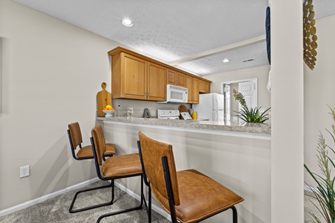 A kitchen with brown chairs and white walls.
