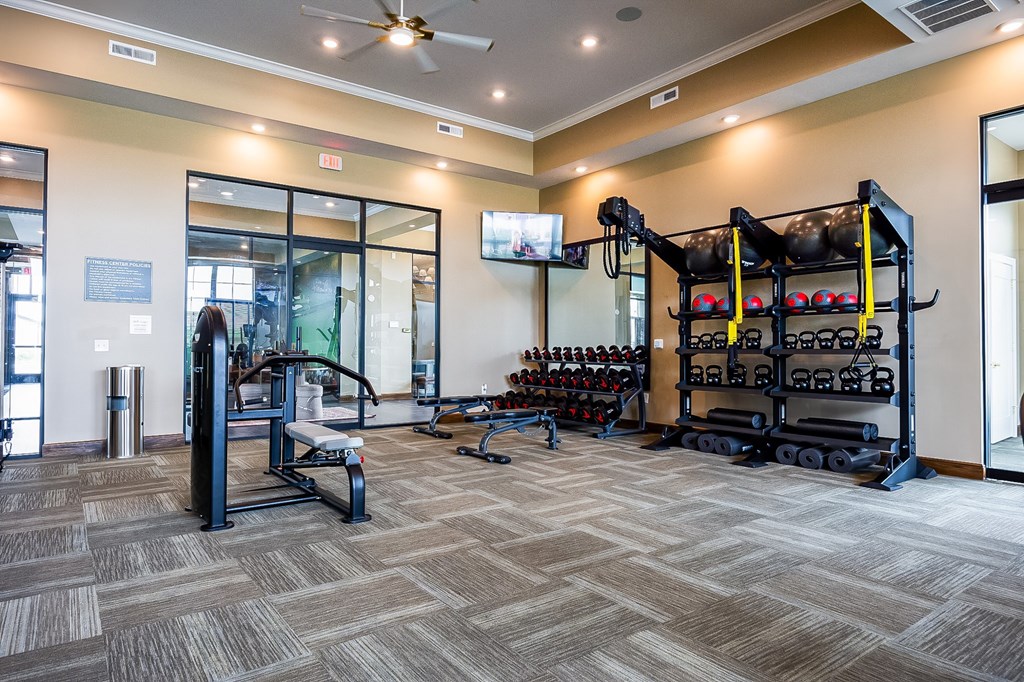 A gym with a variety of equipment including weights and a bench.