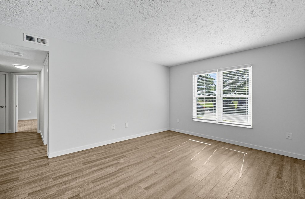 A room with a window and wooden flooring.