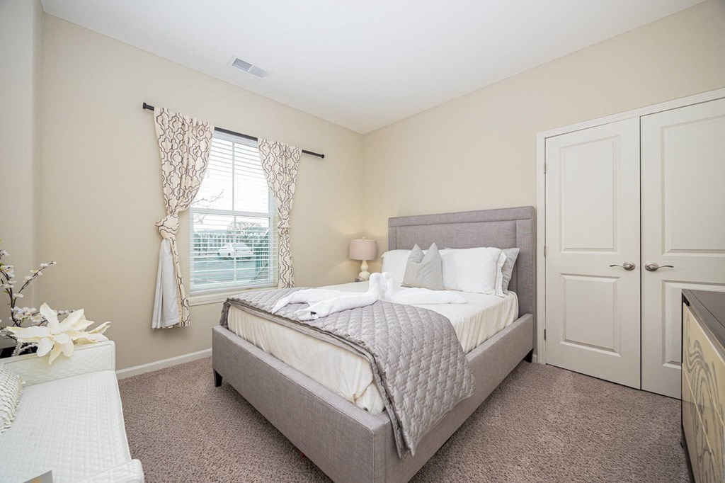 A bedroom with a bed, nightstand, and window.