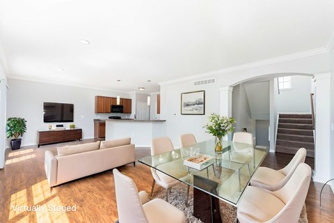 A modern living room with a glass table and white chairs.