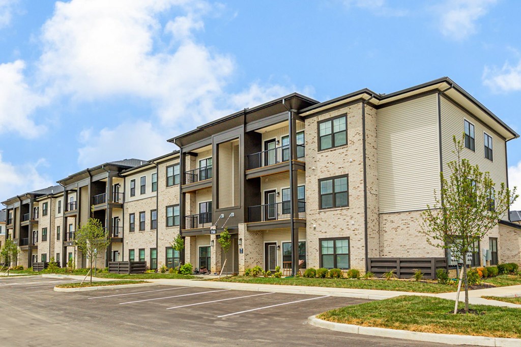 Apartment complex with a parking lot in front.