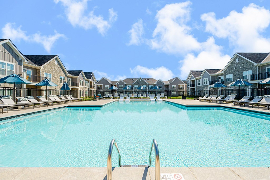 A large swimming pool surrounded by lounge chairs and umbrellas.