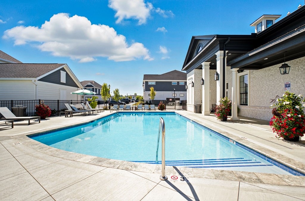 A swimming pool surrounded by a concrete patio and a building in the background.