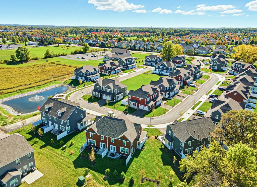 A bird's eye view of a residential neighborhood with houses and a pond.