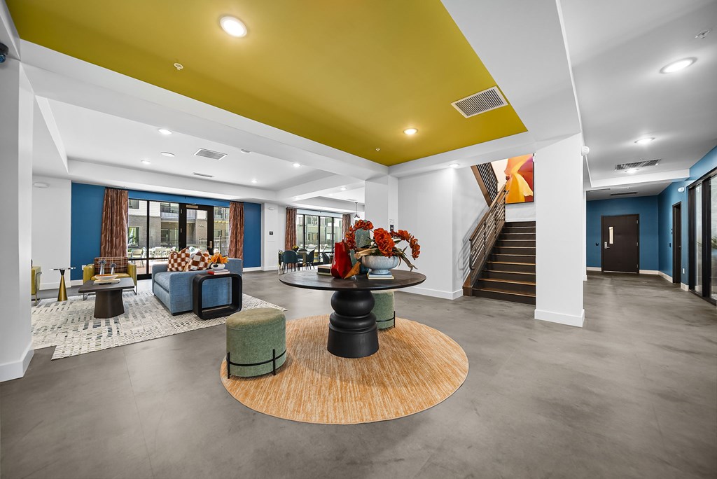 A modern living room with a yellow ceiling and a round wooden table in the center.