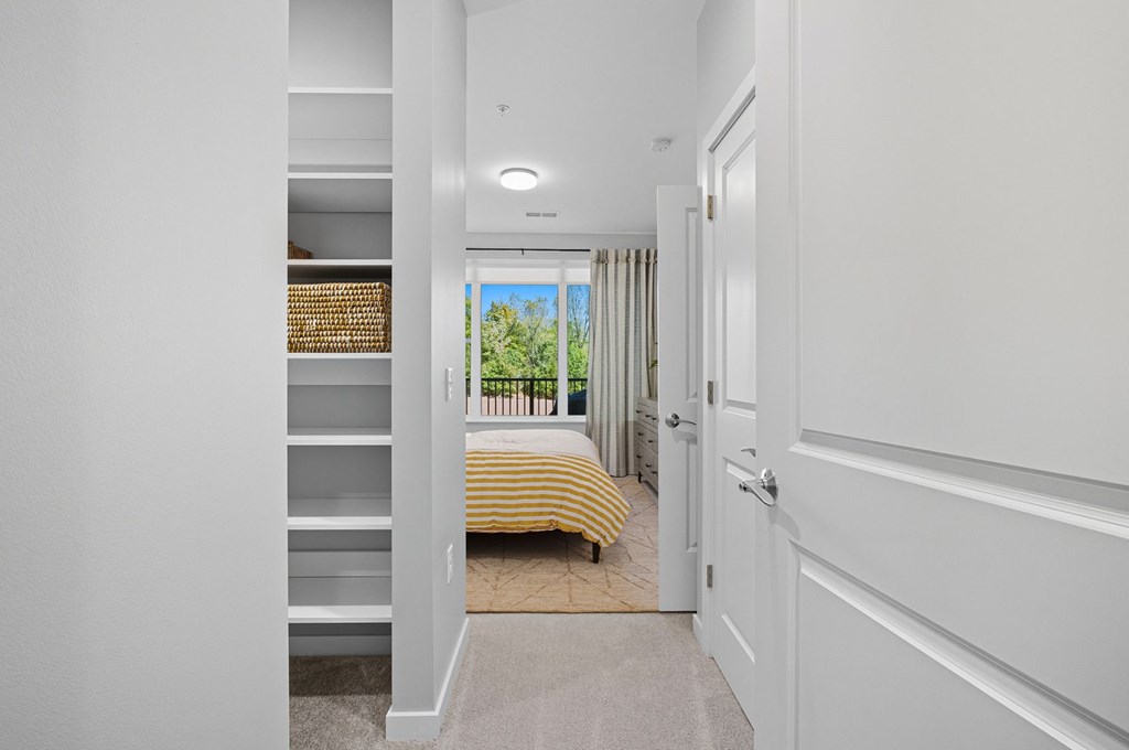A white hallway with a bedroom at the end.