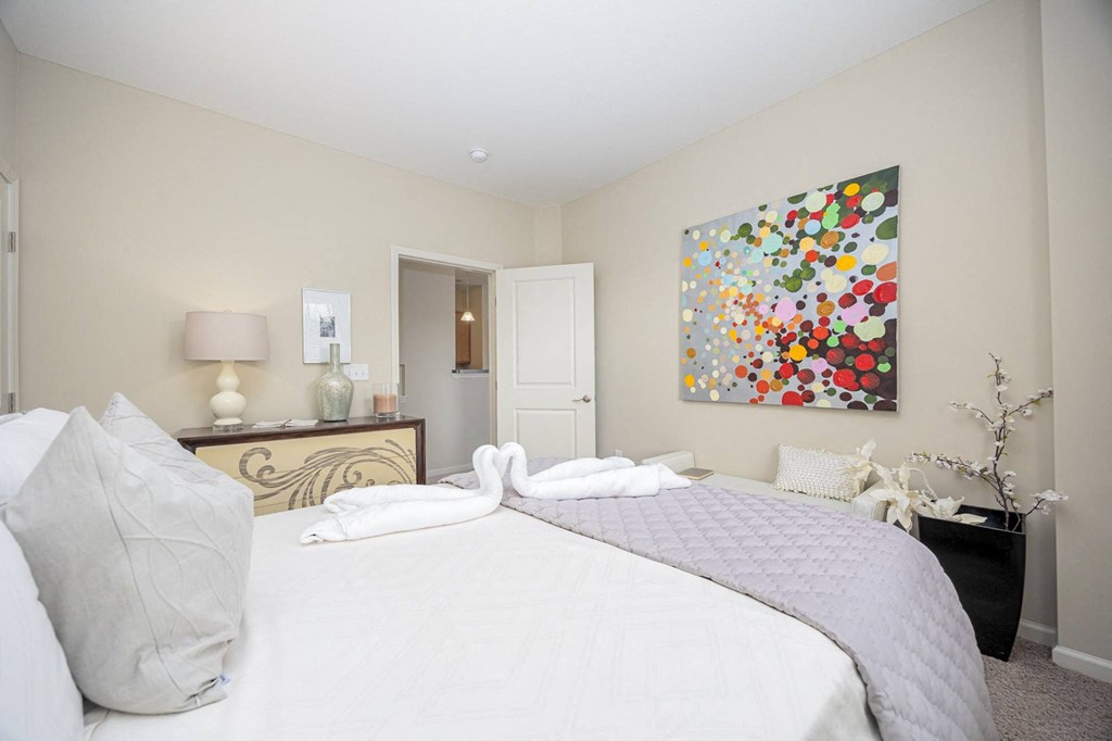 A bedroom with a large bed and a painting on the wall.