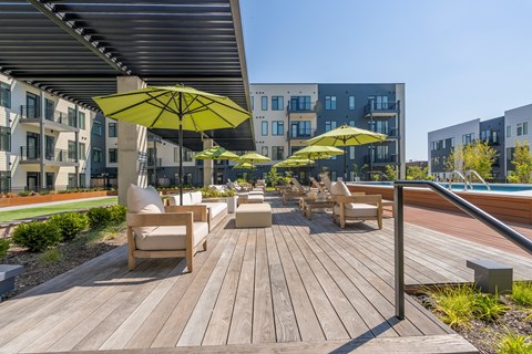 A wooden deck with chairs and umbrellas in front of a building.