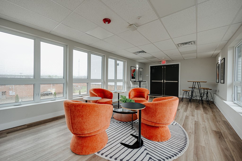 a lounge area with orange chairs and a black and white rug