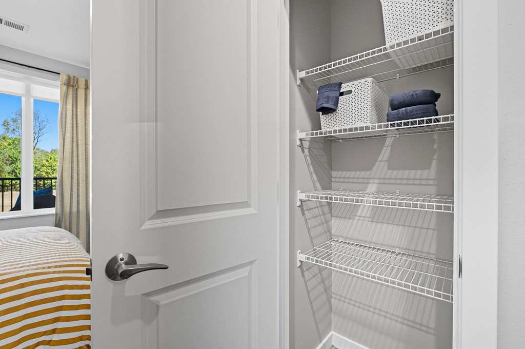 A white, empty, metal shelving unit is in a room with a door.