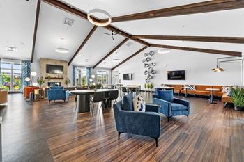 A spacious living room with a dark blue sofa and wooden floors.