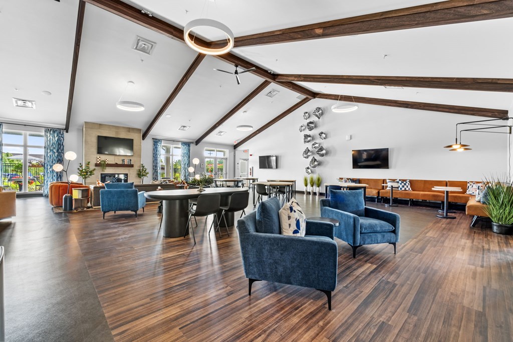 A spacious living room with a dark blue sofa and wooden floors.