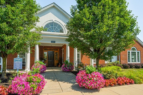 the front of a brick building with flowers and trees