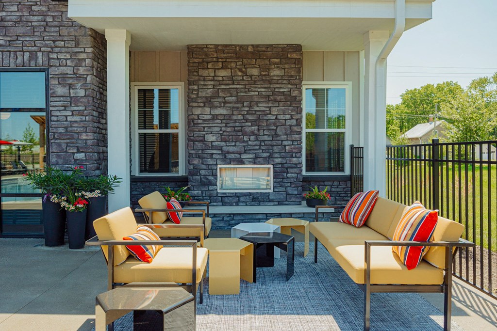 a patio with furniture and a fireplace on the side of a house