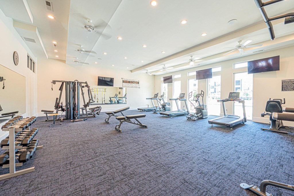 a gym with weights and cardio equipment in a building with windows