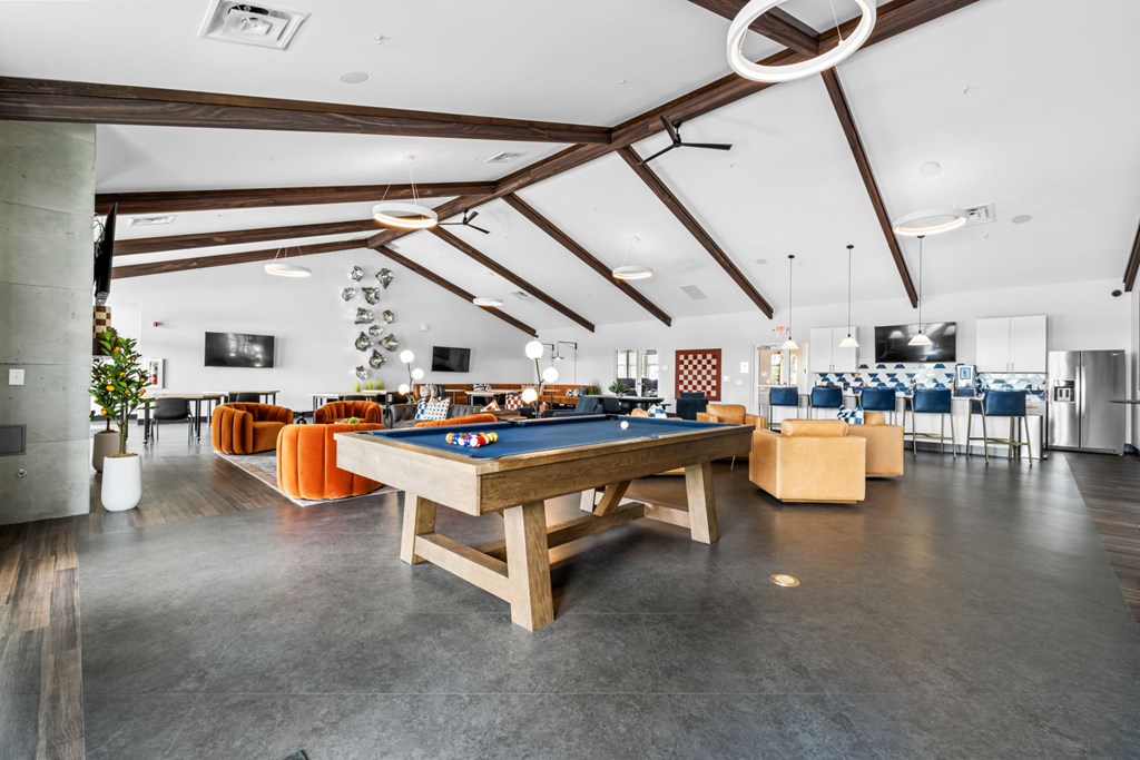 A billiard table is in the middle of a room with a concrete floor and a high ceiling.