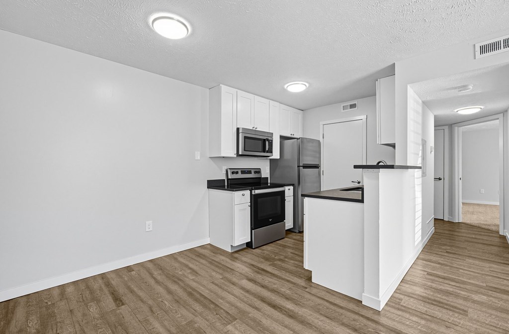A kitchen with white cabinets and a wooden floor.