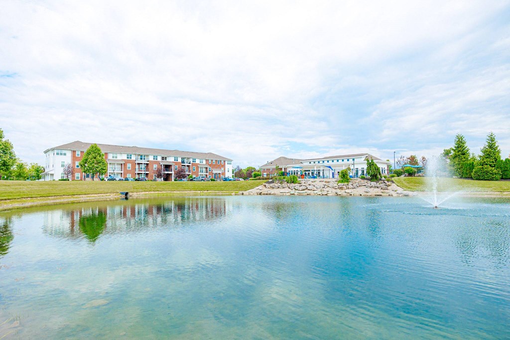 a pond with a fountain in front of a building