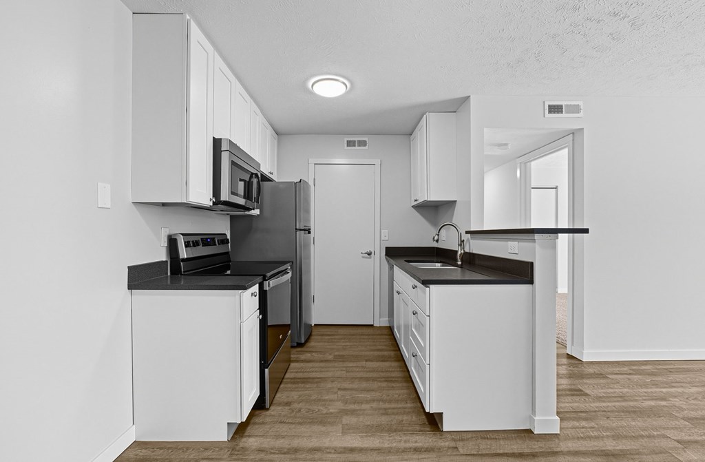 A modern kitchen with white cabinets and a black countertop.
