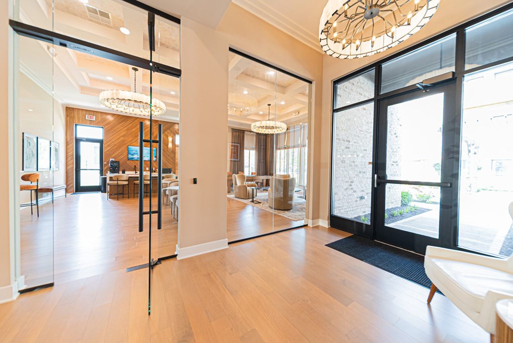A large, open living room with a wooden floor and a glass door leading to a balcony.