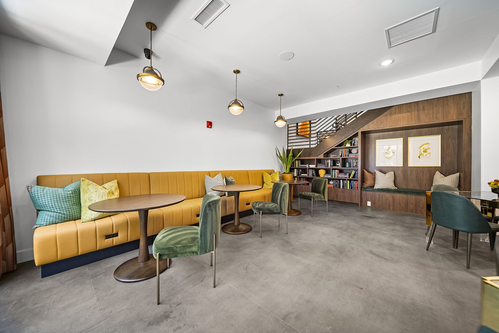 A room with a yellow couch and a grey floor.