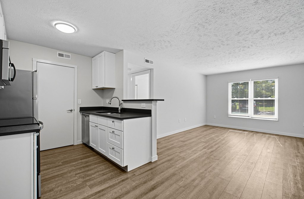 A kitchen with white cabinets and a black countertop.