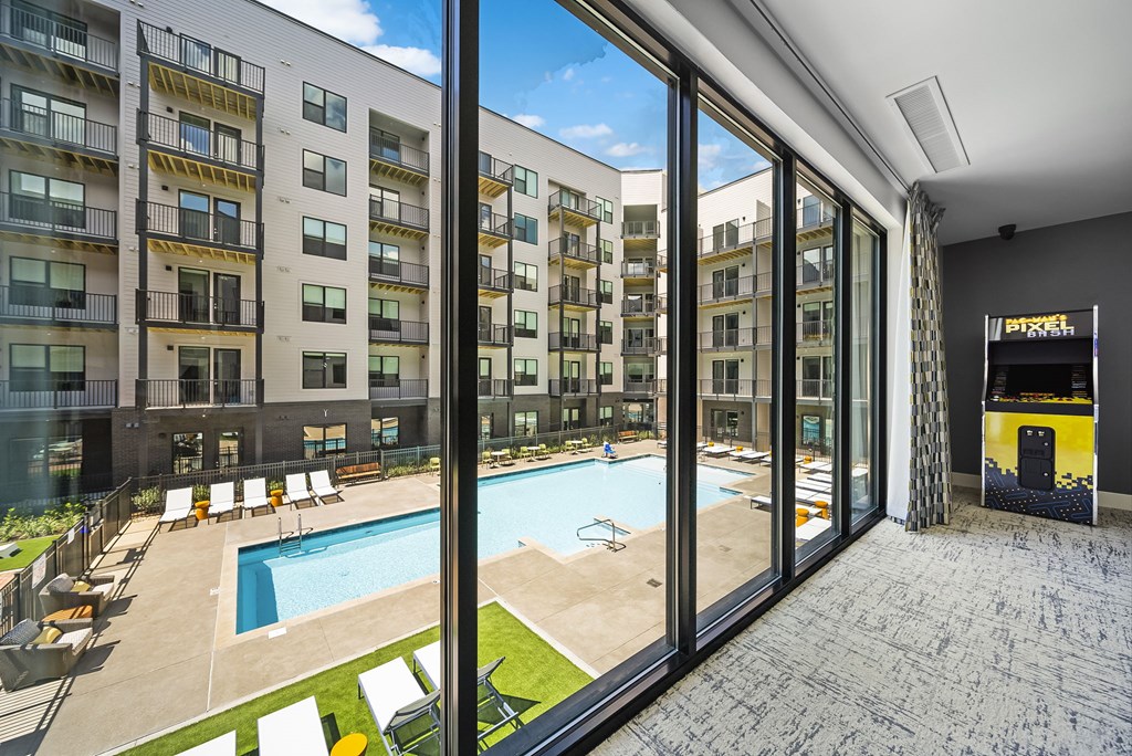 A view from inside a building looking out to a pool and sun loungers.