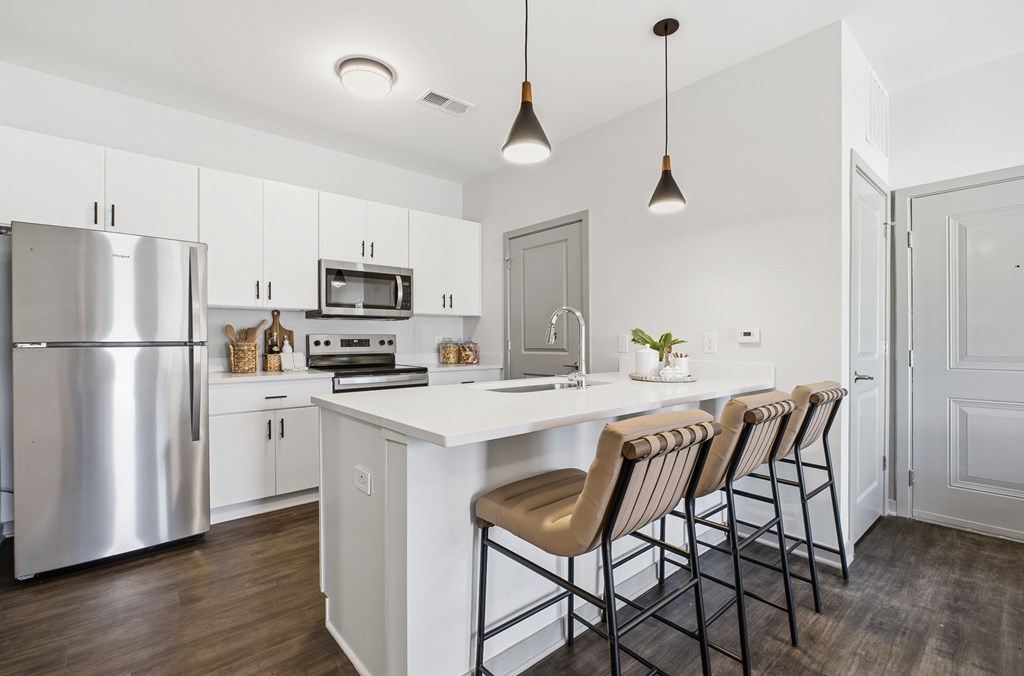 A modern kitchen with a white island and stainless steel appliances.