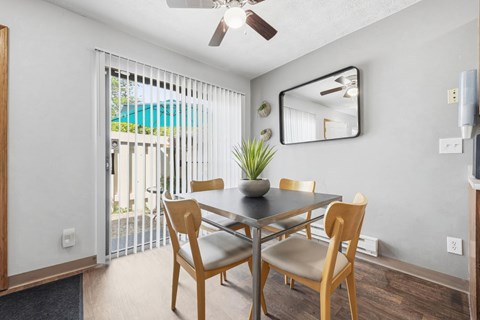 A dining room with a table and chairs and a ceiling fan.