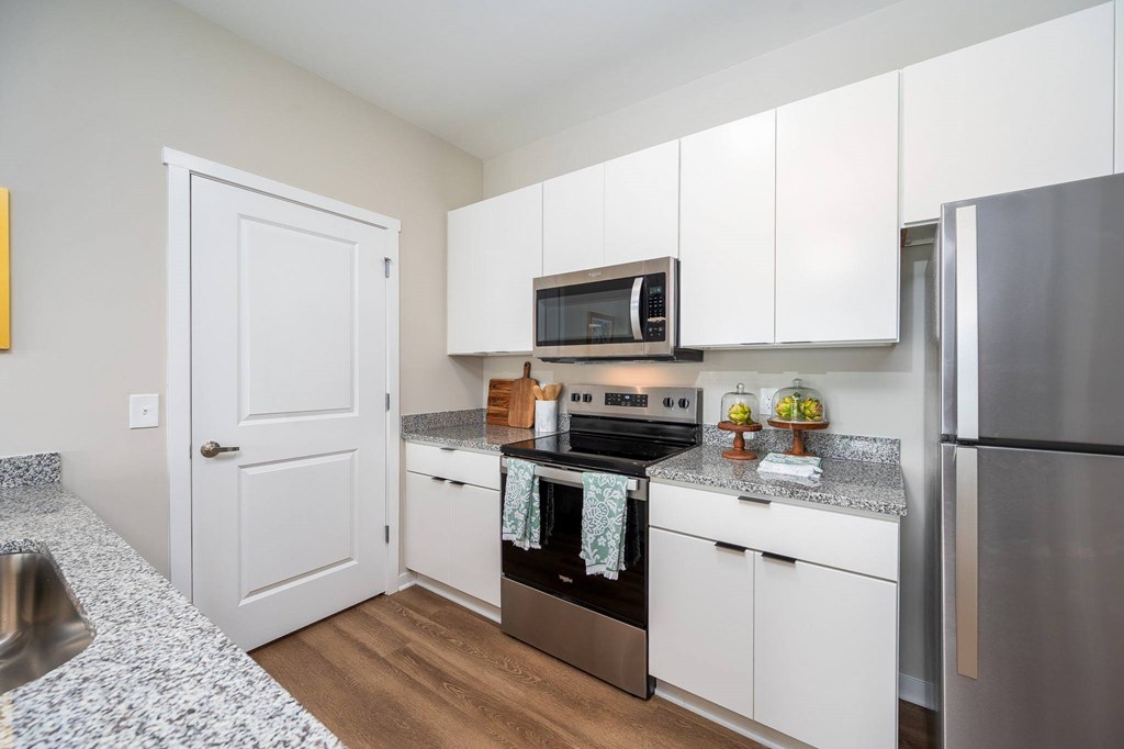 A kitchen with white cabinets and a stainless steel refrigerator.