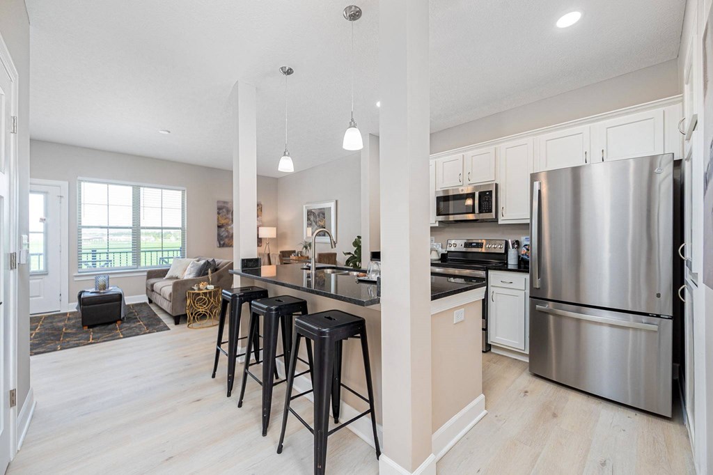 an open kitchen and living room with stainless steel appliances and bar stools