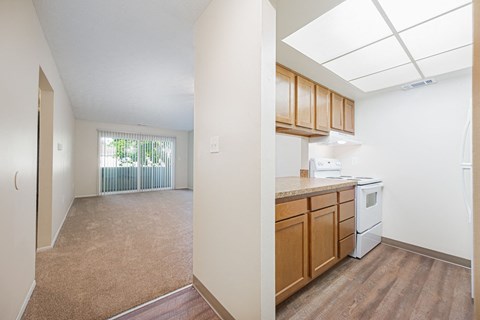 an empty kitchen and living room with wood flooring and a window