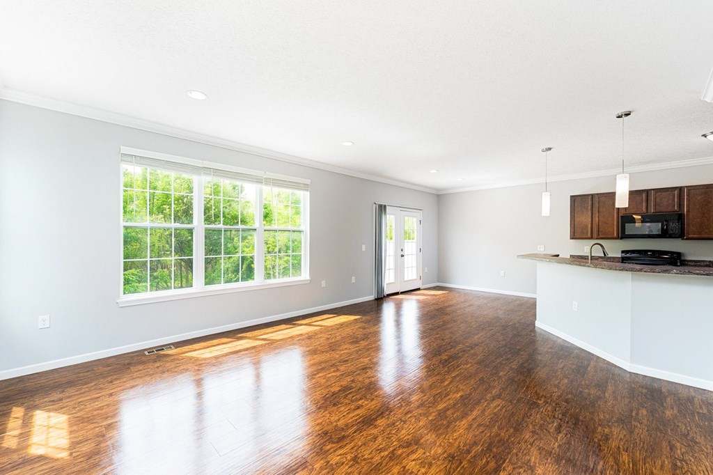 A spacious kitchen and living room with wooden floors and white walls.