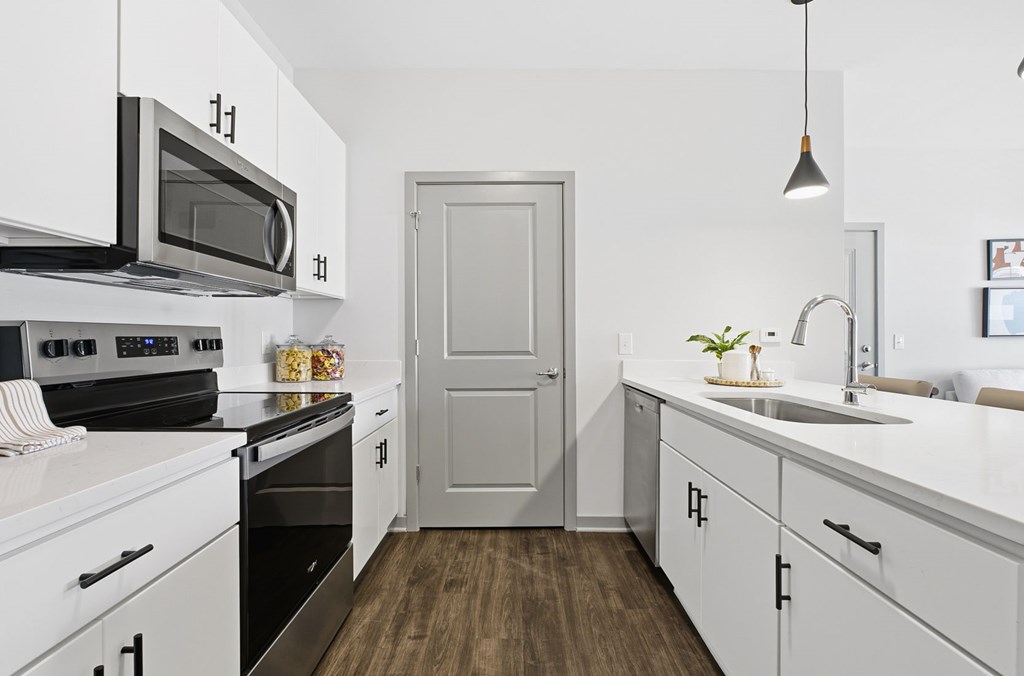 A modern kitchen with white cabinets and a grey door.