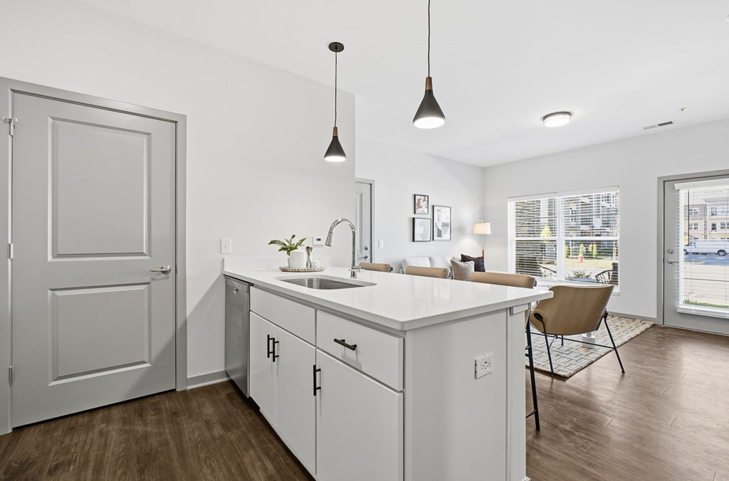 A kitchen with white cabinets and a wooden floor.
