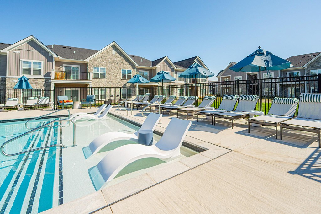 A large swimming pool with lounge chairs and umbrellas in front of a resort.