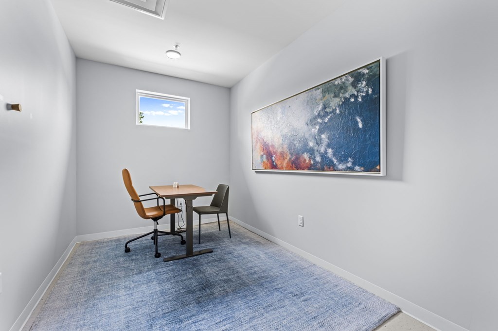A room with a table and chairs and a painting on the wall.