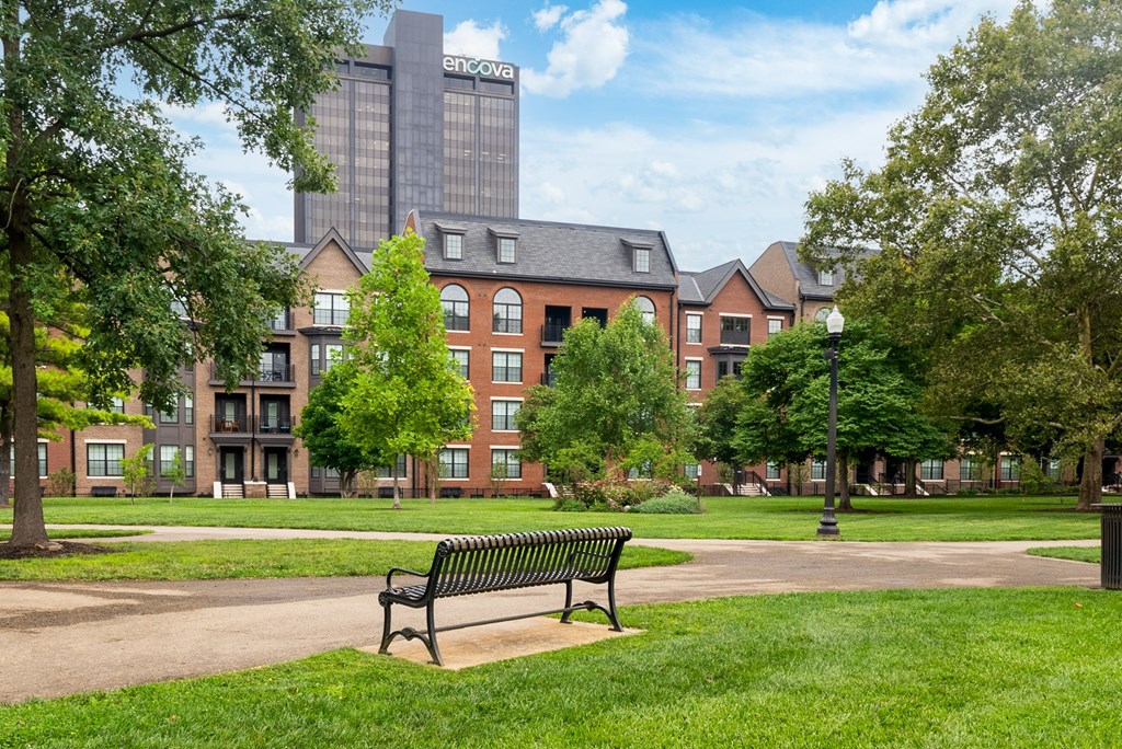 a park bench in the middle of a grassy area with a building in the background