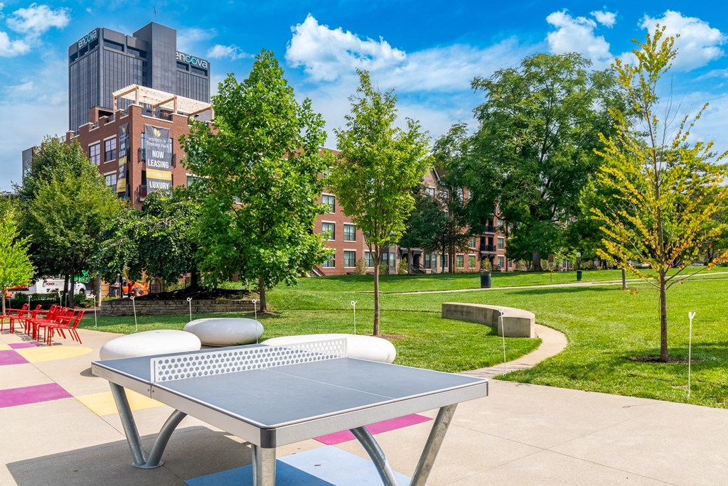 a ping pong table in a park with trees and buildings in the background